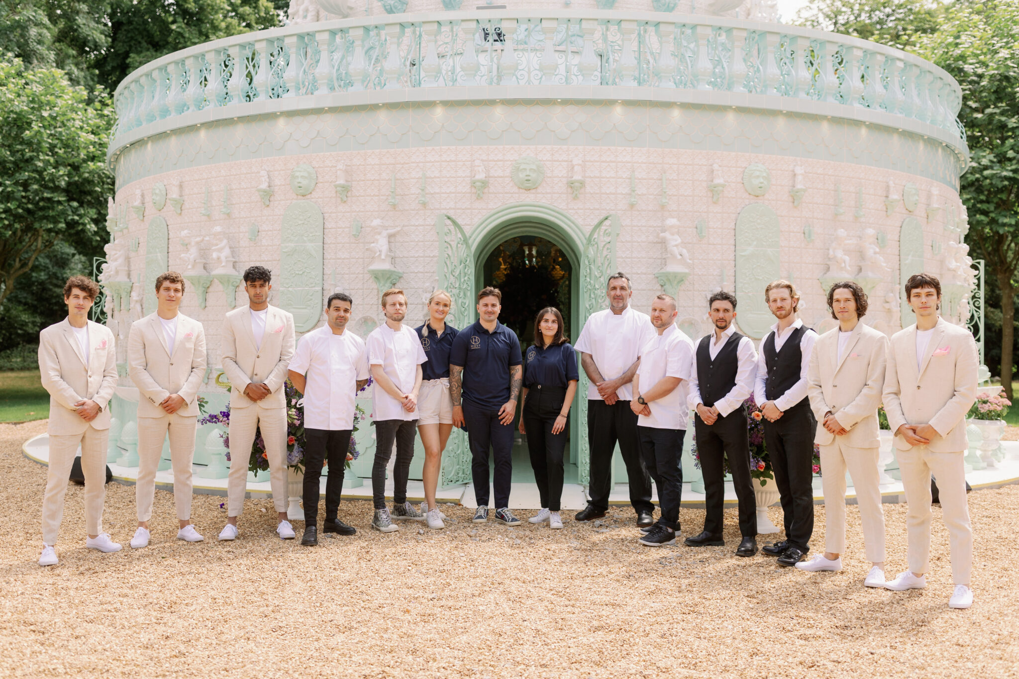 row of staff, waiters, chefs, managers in front of large cake building