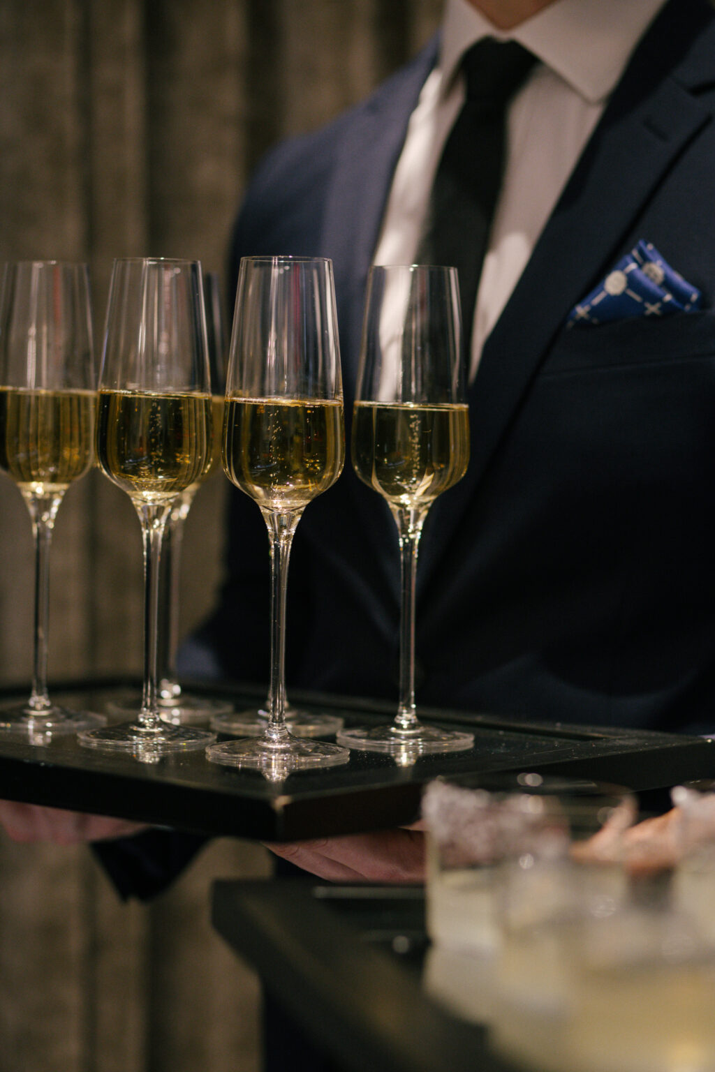 waiter wearing a suit with tie holding champagne flutes