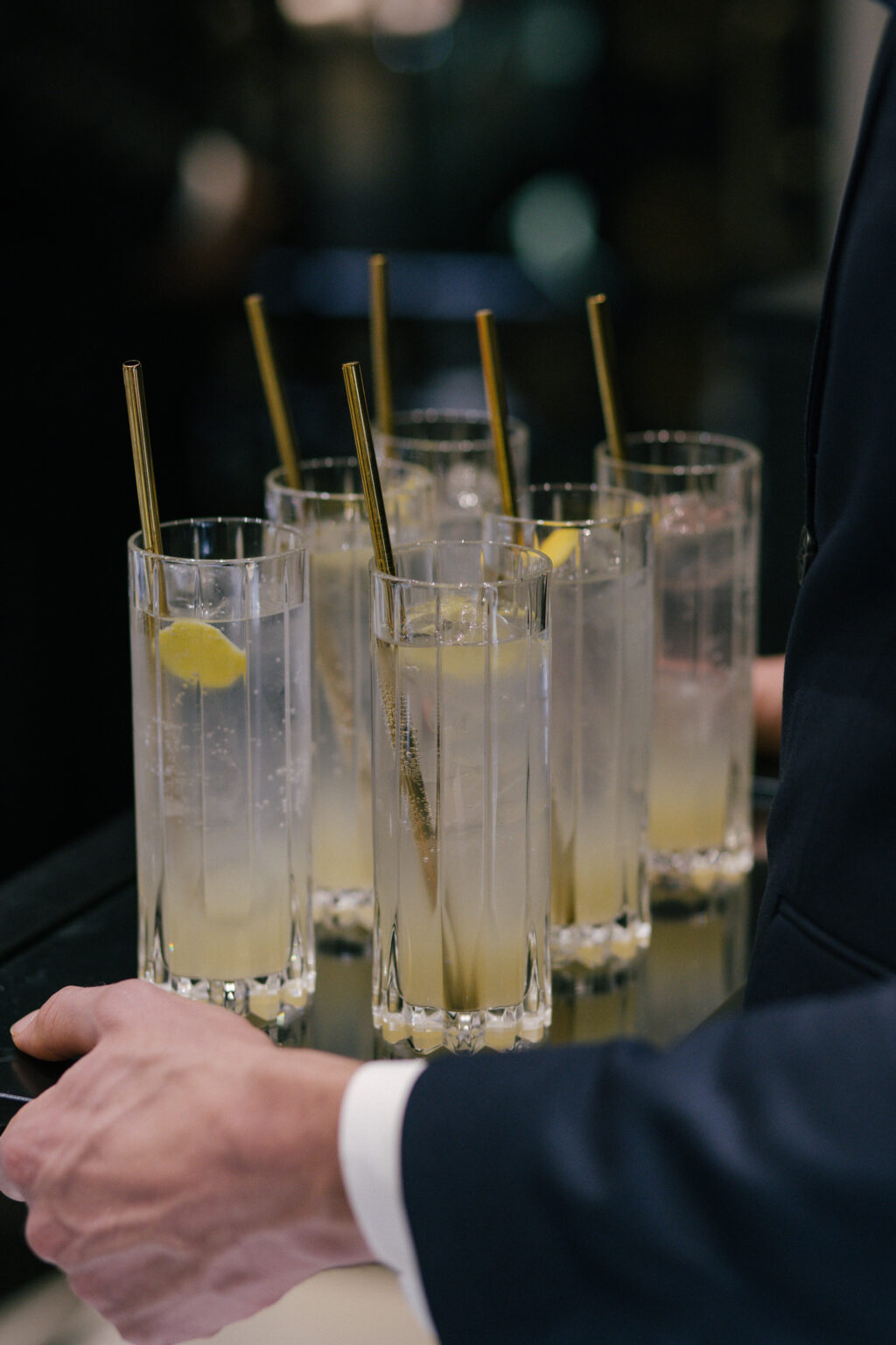 six clear mocktails in tall glasses with gold metal straws