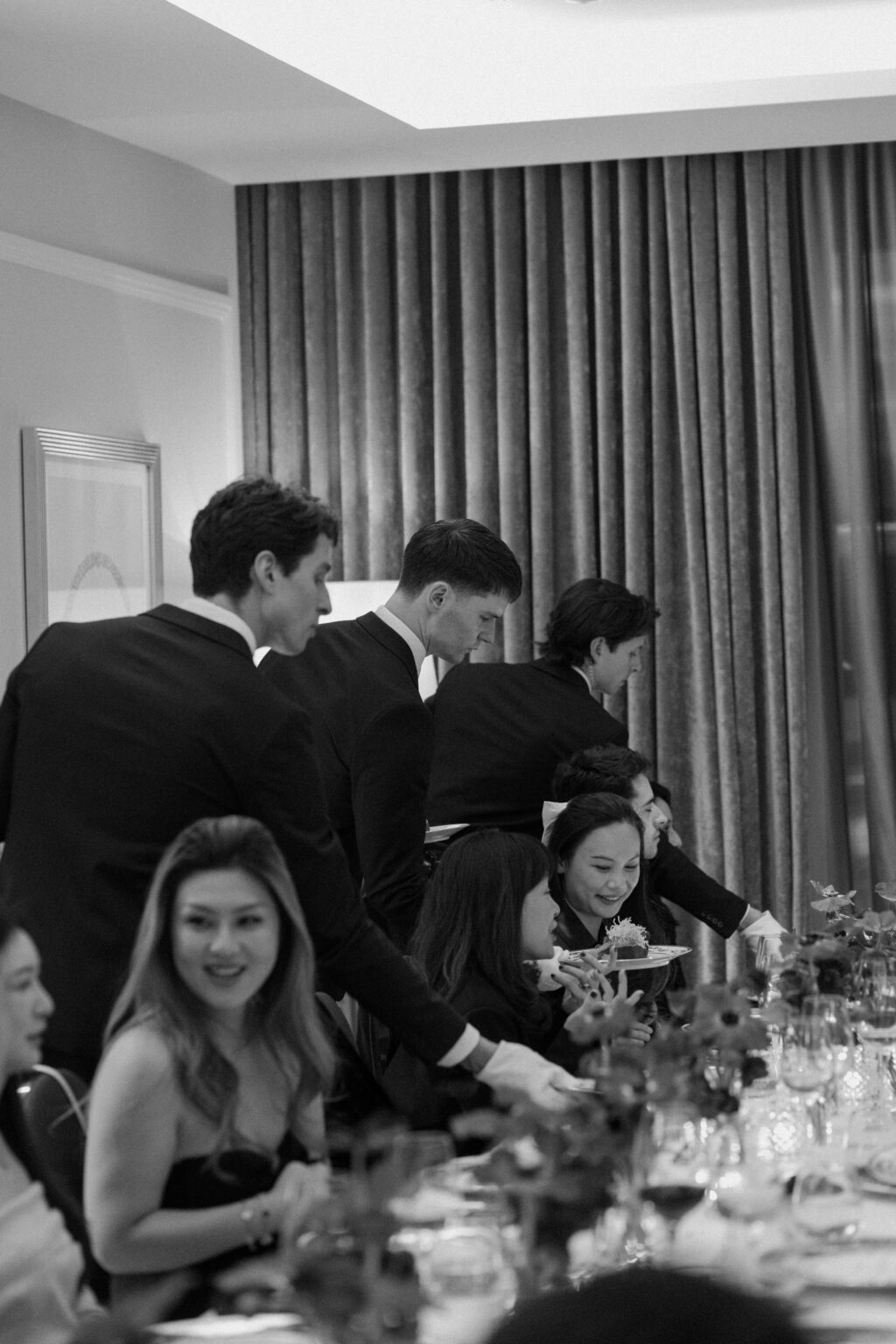 three waiters serving food to guests at the table