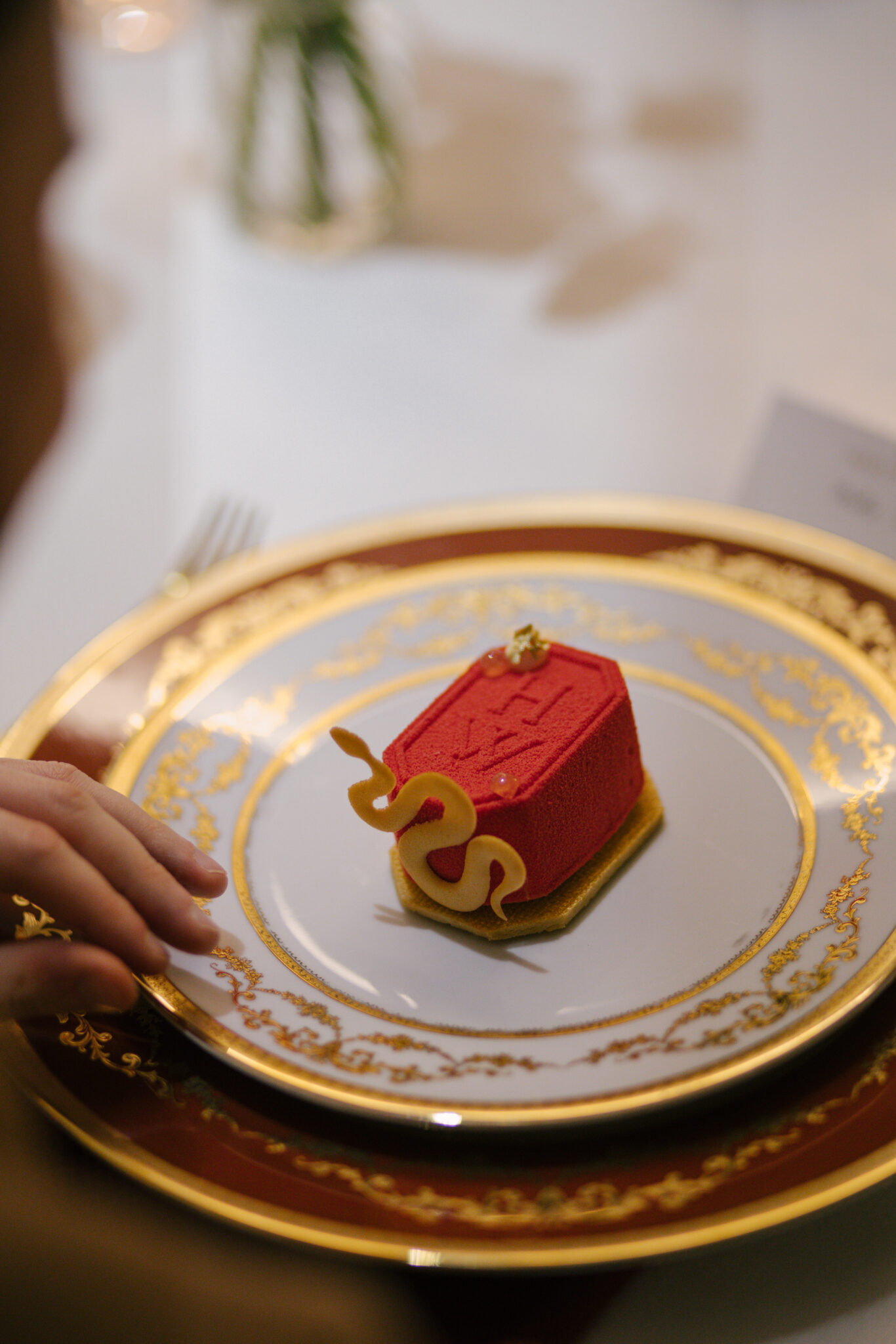 pink branded dessert with snake tuille on white and gold detailed plate