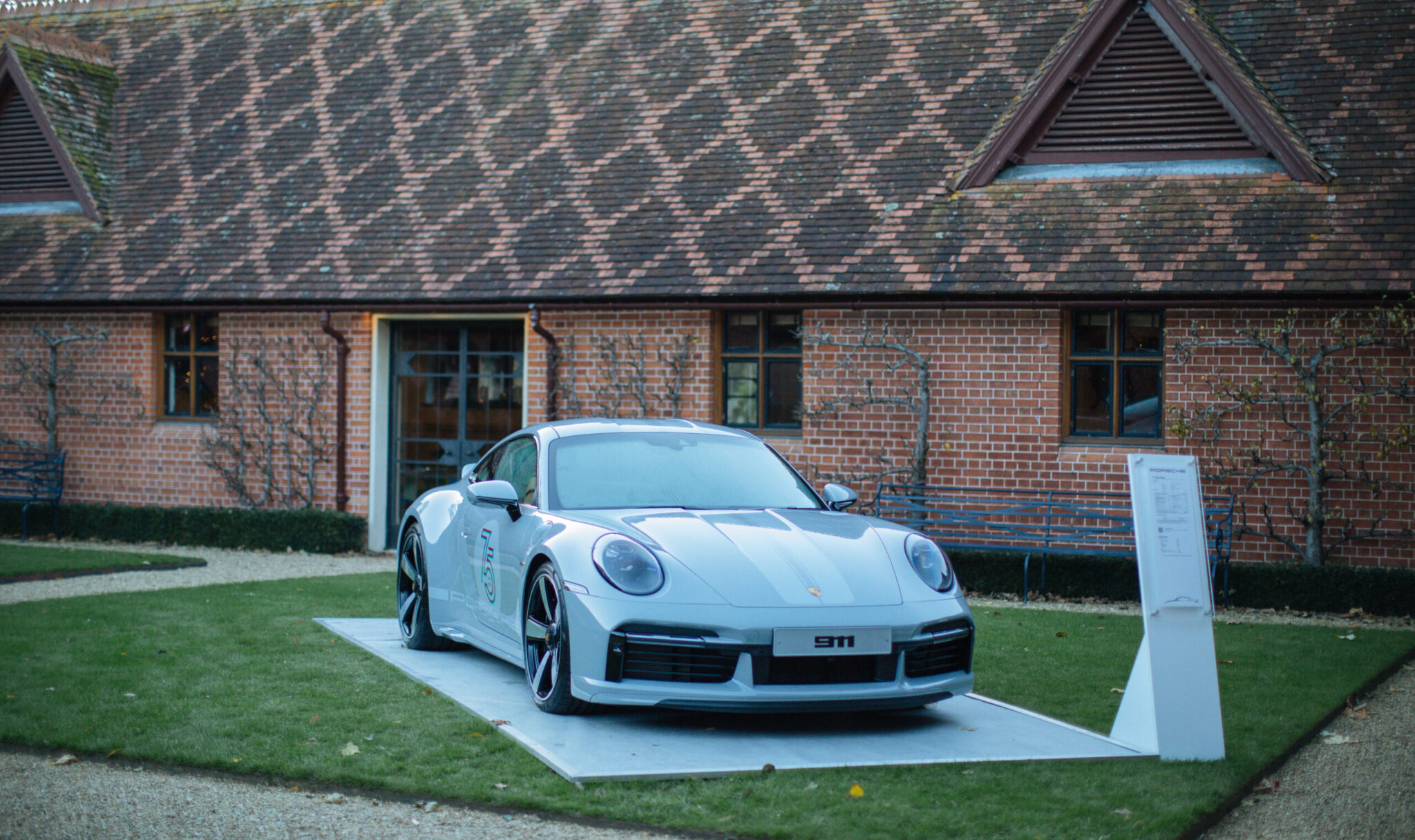porsche 911 grey parked on grass background building