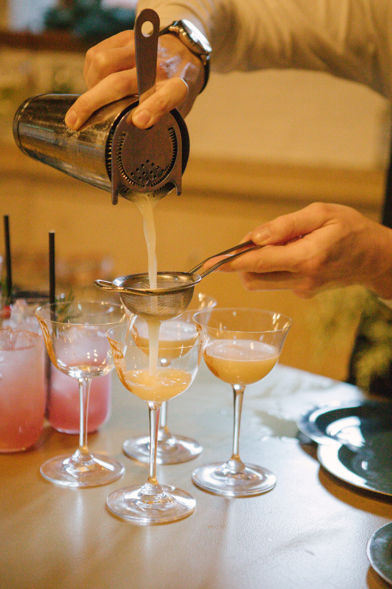 bartender pouring cocktails into glasses yellow red