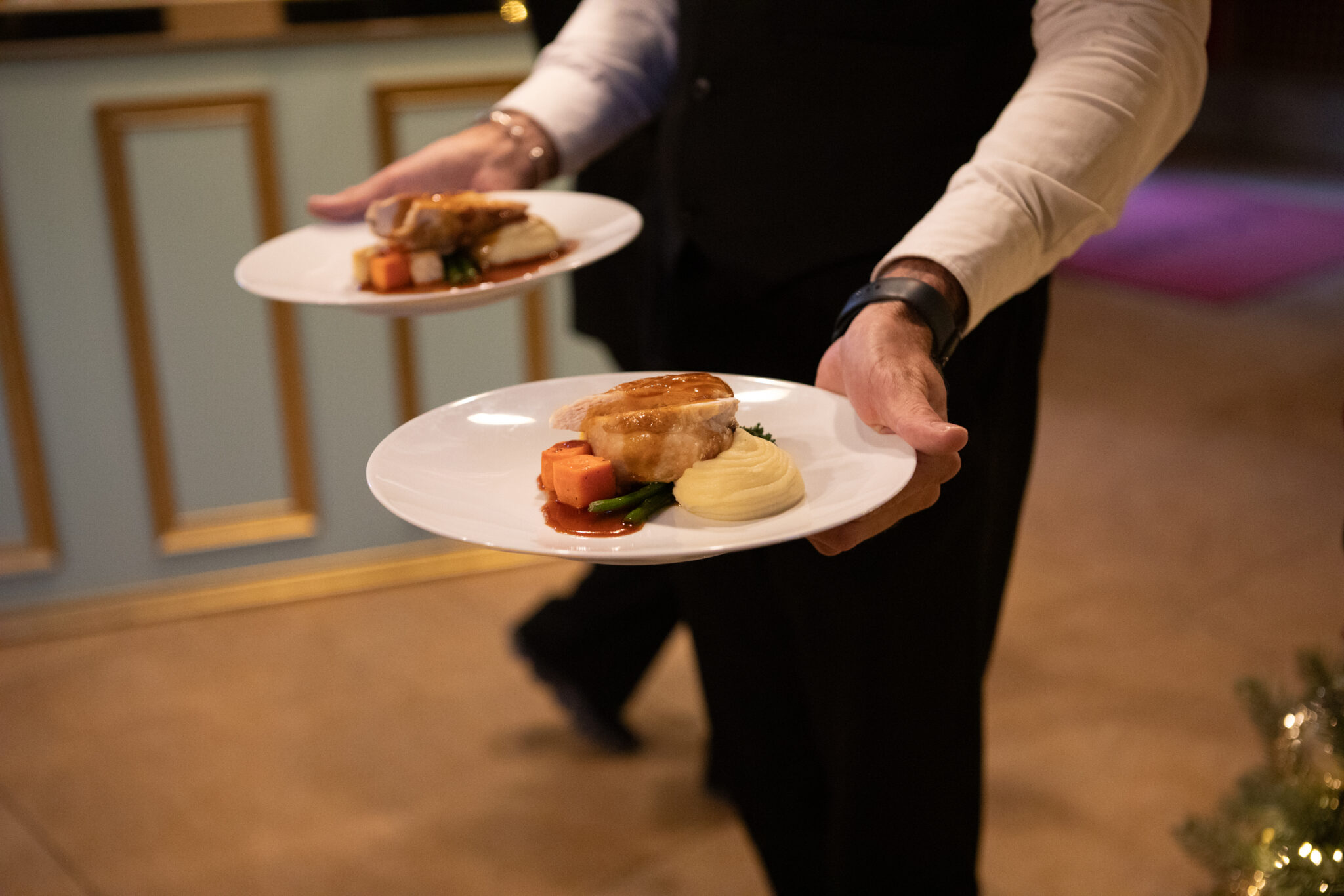 waiter carrying two plates of food on white dishes